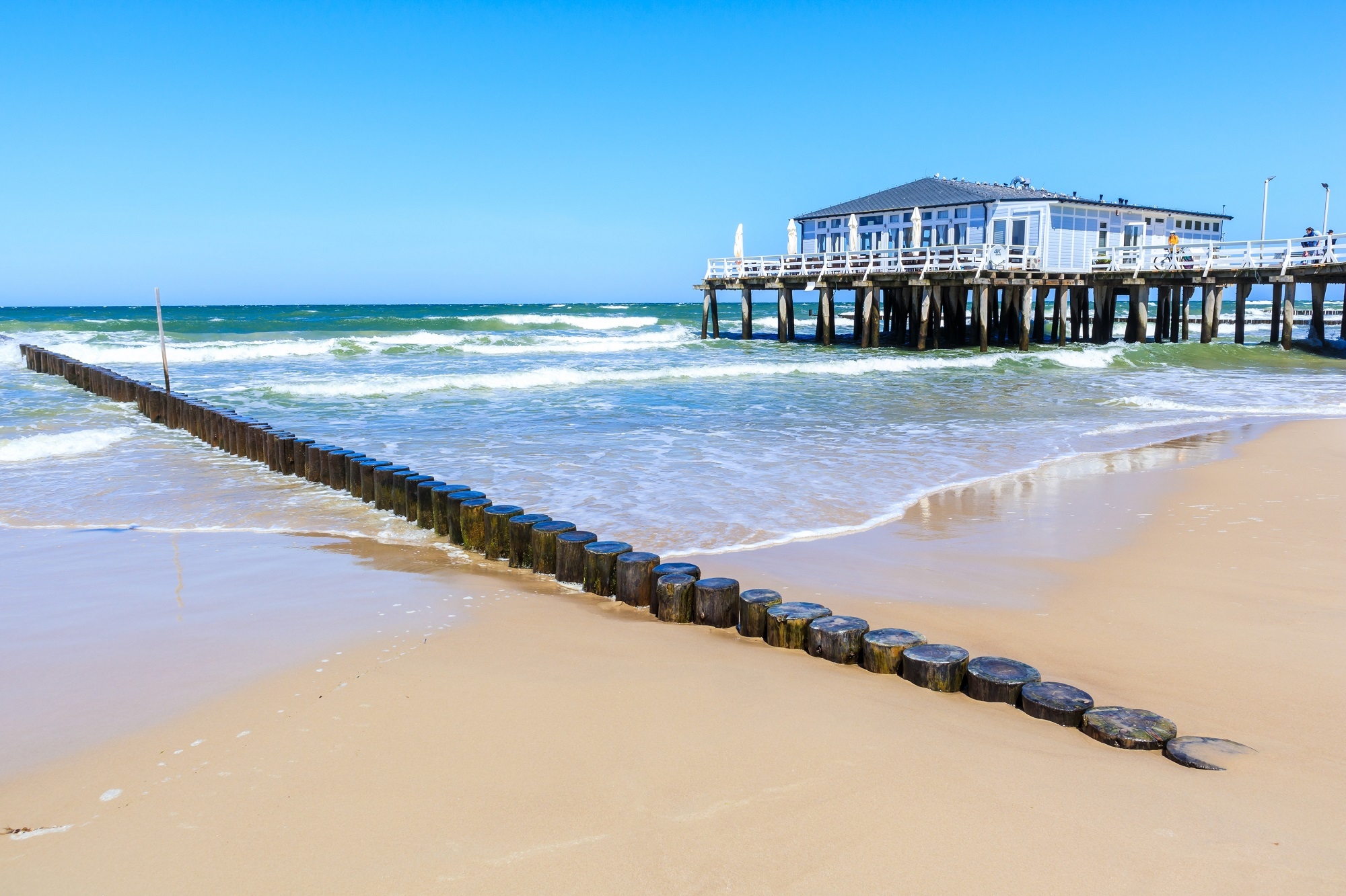 Pier und schöner weißer Sandstrand mit blauem Meer im Dorf Ustronie Morskie, Ostseeküste, Polen